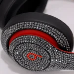 Swarovski Beats Studio Pro crystal work, shown on an earlier Beats Studio model: close-up of an outer ear cup in dark grey crystals, the b logo in red crystals beside that model’s red trim