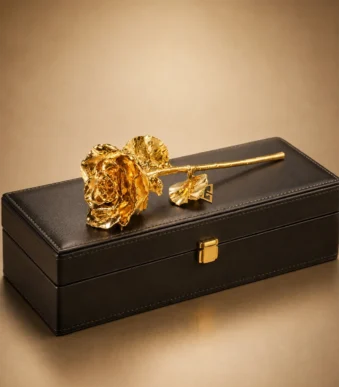 24K Gold-Dipped Rose lying on a black leather presentation box, its petals, leaves and long stem finished in gold